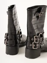 Botas cortas de cuero marrón con textura, hebillas ajustables, apliques circulares y punta cuadrada.