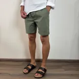 Bermuda color verde militar, de corte recto y largo a la rodilla, con cintura ajustable con cordón y bolsillos laterales. Confeccionada en simil lino.