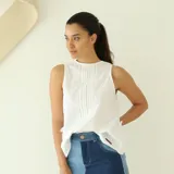 Musculosa blanca con bordado calado y detalle de pinzas verticales en el frente.