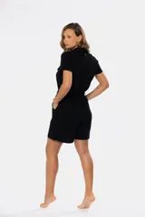 Mono corto negro de lino con cuello camisero, cierre frontal con botones de madera, bolsillos laterales y cinturón del mismo tejido.