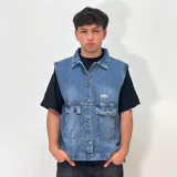 Chaleco de jean azul con cuello clásico, cierre con botones metálicos, dos bolsillos con solapa en el pecho, logo bordado en el pecho y corte recto.