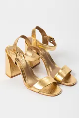 Sandalias de tacón alto color lila, con tira delantera y tobillera con hebilla dorada.