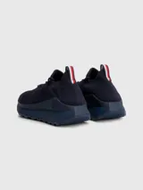 Zapatillas de running Tommy Hilfiger color azul marino, confeccionadas en tejido de punto elástico de poliéster reciclado. Cuentan con plantilla de acupresión, suela dentada de goma y caucho, trabilla distintiva y monograma TH grabado en la entresuela.