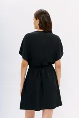 Vestido corto negro de poliéster, con escote cruzado, mangas cortas y cintura elastizada.