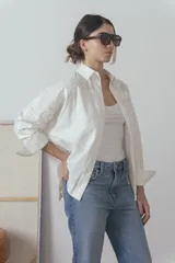 Camisa blanca de manga larga con cuello clásico y cierre frontal con botones.