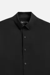 Camisa de vestir verde oscuro, corte slim fit, con cuello italiano, mangas largas con puños abotonados y cierre frontal con botones.