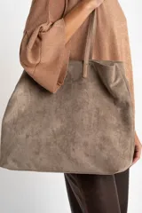 Bolso tipo tote de gamuza vegana color camel, con asas de mano y logo grabado en el frente.