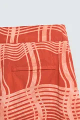 Short de baño color ladrillo con estampado de líneas curvas en color salmón. Tiene cintura elástica ajustable con cordón, bolsillos laterales y trasero.