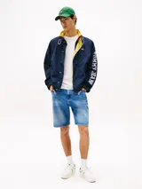 Campera Tommy Jeans azul marino con interior amarillo, cierre con botones a presión, cuello alto, cordón ajustable en la cintura, dos bolsillos delanteros y logo de la marca en la manga.