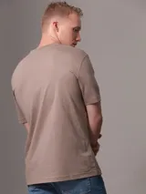 Remera color beige con cuello redondo y mangas cortas. Estampado frontal con diseño de sello de la ciudad de Nueva York y monograma bordado.