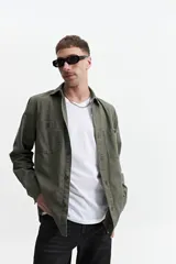 Sobrecamisa color marrón claro de twill de algodón, con cuello clásico, cierre frontal con botones a tono, dos bolsillos de parche con solapa abotonada en el pecho y mangas largas con puños abotonados.