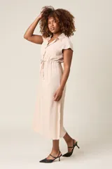 Vestido camisero color beige con cuello, botones frontales, mangas cortas y lazo ajustable en la cintura.