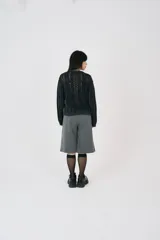 Sweater negro de punto calado con cuello en V y corte holgado. Diseño con efecto desgastado y detalles de hilos rotos, que aporta un estilo vintage.