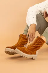 Bota de caña media color marrón óxido, confeccionada en cuero gamuzado. Presenta cierre frontal con cremallera, suela track color beige y detalle de pieza de cuero en la parte trasera del tobillo.