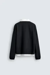 Polo negro de corte relaxed fit confeccionado en tejido con algodón. Cuello solapa con cierre frontal de botonadura. Manga larga. Bajo con aberturas laterales. Acabados en rib.