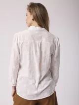 Camisa blanca de algodón con bordado floral, corte clásico, cuello camisero y mangas largas con puños abotonados.