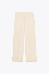 Pantalón de vestir color crema, de tiro alto y pernera ancha, con pinzas delanteras, bolsillos frontales y falsos bolsillos de doble vivo en la espalda.
