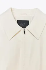 Chaqueta bomber color crudo con cuello solapa, manga larga con puño elástico interior, bolsillos laterales, forro interior, bajo acabado en elástico y cierre frontal con cremallera.