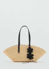 Bolso playero de paja color beige, con asas de cuero sintético negro y apliques de flores negras.
