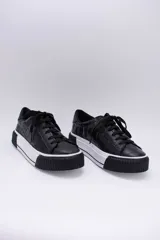 Zapatillas bajas color marrón con textura simil cuero de cocodrilo, cordones al tono y suela de goma blanca con detalle marrón.