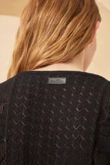 Top color crema de tejido calado con cuello en V, manga corta y cierre frontal con botones. Tiene un lazo ajustable en la cintura.