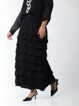 Falda larga negra con cintura elástica y múltiples volantes horizontales.