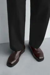 Bota estilo Chelsea de cuero negro, con elásticos laterales y suela plana a tono con ligero tacón.