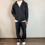 Campera con capucha de algodón color gris oscuro con efecto lavado y cierre frontal. Tiene bolsillos laterales y puños ajustados.
