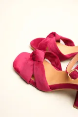 Sandalia de terciopelo verde con taco cuadrado de 7 cm, punta cuadrada y tiras anchas anudadas en el empeine. Cuenta con una tira fina ajustable al tobillo con hebilla dorada.