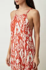 Vestido midi con estampado abstracto en tonos naranja y blanco, breteles finos y corte evasé.