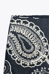 Falda pantalón corta de tiro alto color azul denim con bordados florales blancos.