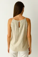 Top de lino y viscosa color blanco roto, de corte ajustado al cuerpo, con escote halter y tirantes finos. Presenta un detalle de frunces en el frente y cierre frontal con botones.
