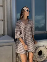 Vestido corto tejido a rayas horizontales marrones y blancas, con escote en V y mangas anchas.