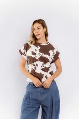 Remera blanca con estampado de manchas de vaca en color marrón, de corte recto y mangas cortas con dobladillo.