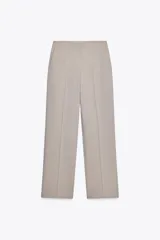 Pantalón de vestir color beige, de tiro alto, corte recto y bolsillos laterales.