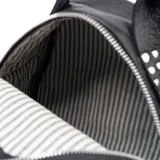 Mochila pequeña negra de cuero con tachas plateadas en el bolsillo frontal. Tiene asa de mano y correas regulables.