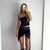 Minifalda negra de tul con volados asimétricos y cintura con elástico. Incluye cinturón negro con tachas doradas.