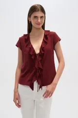 Blusa blanca de viscosa con escote en V, mangas cortas y volados frontales con lazo ajustable.