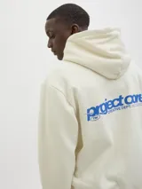 Buzo con capucha color crema, de manga larga y corte holgado. Tiene bolsillo tipo canguro y logo estampado en el pecho.