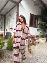 Camisa de tejido de punto oversize con botones en el frente y diseño a rayas horizontales en tonos beige, rojo, marrón y celeste.