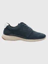 Zapatillas Hush Puppies modelo Goss, color azul marino, confeccionadas en cuero, con detalles metalizados en el talón y cordones. Suela de EVA con tecnología Zero G y plantilla Bloom de algas recicladas.