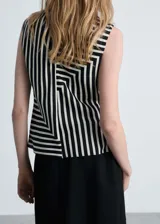 Blusa sin mangas de tejido fluido satinado con estampado de rayas verticales en blanco y negro, cuello Perkins y cierre de cremallera en la parte posterior.