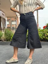 Pantalón capri negro de tiro alto, corte ancho y largo midi.