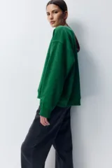 Buzo verde con cuello redondo, puños y bajo acanalados. Estampado frontal con la palabra "SOHO" y el número "95" en color blanco.