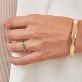 Anillo de oro amarillo 18k con esmeralda ovalada y pequeños brillantes alrededor.