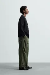 Pantalón verde militar de corte relaxed fit confeccionado en tejido técnico ligero. Cuenta con cintura elástica ajustable con cordón interior, bolsillos frontales y traseros con solapa, pliegues en las rodillas y bajo ajustable con elástico.