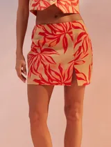 Minifalda color beige con estampado de hojas rojas y abertura lateral.