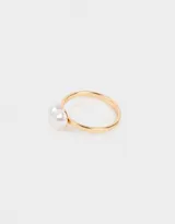 Anillo dorado con una perla blanca en forma de corazón.
