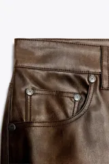 Pantalón de tiro alto color marrón con efecto piel, corte bootcut, cinco bolsillos y cierre frontal con cremallera y botón.