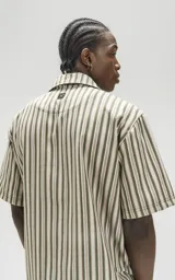 Camisa oversize de manga corta con cuello abierto y estampado a rayas verticales en tonos verde y beige.